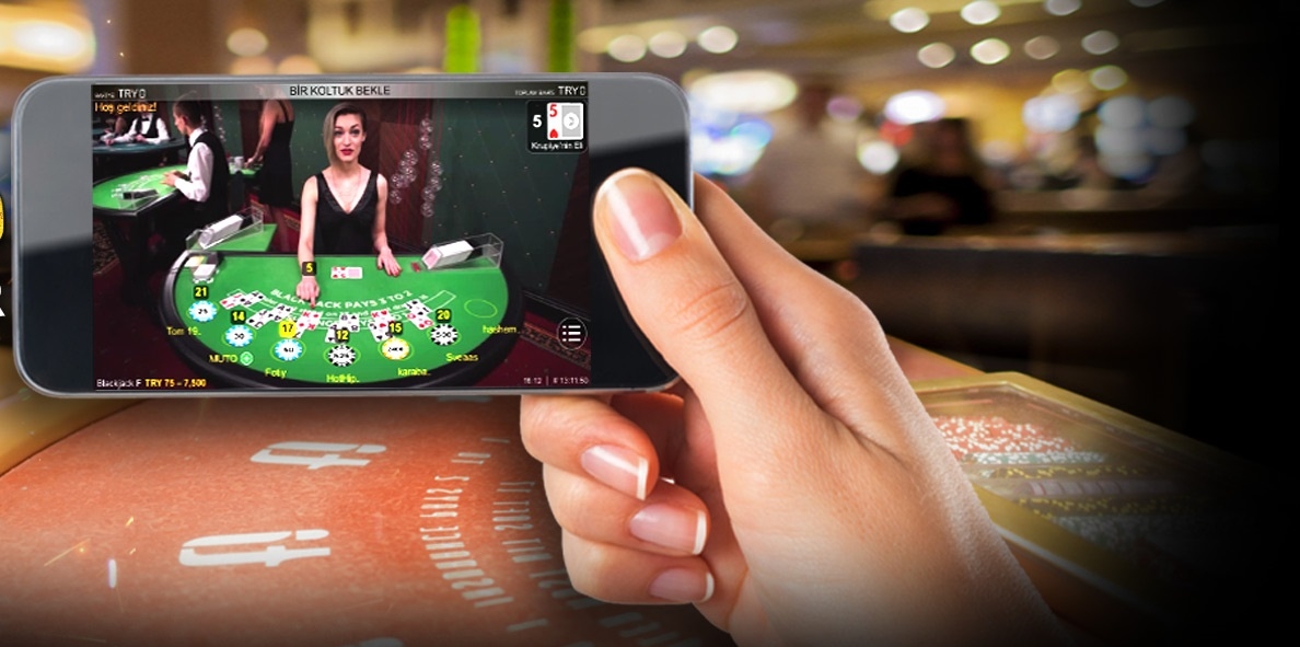 Игрок, находясь в казино, смотрит трансляцию лайв блэкджека со смартфона